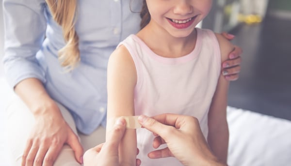 Girl having a bandage applied to her arm after getting a shot